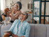 A photo of a husband and wife playing with their dog on the family sofa